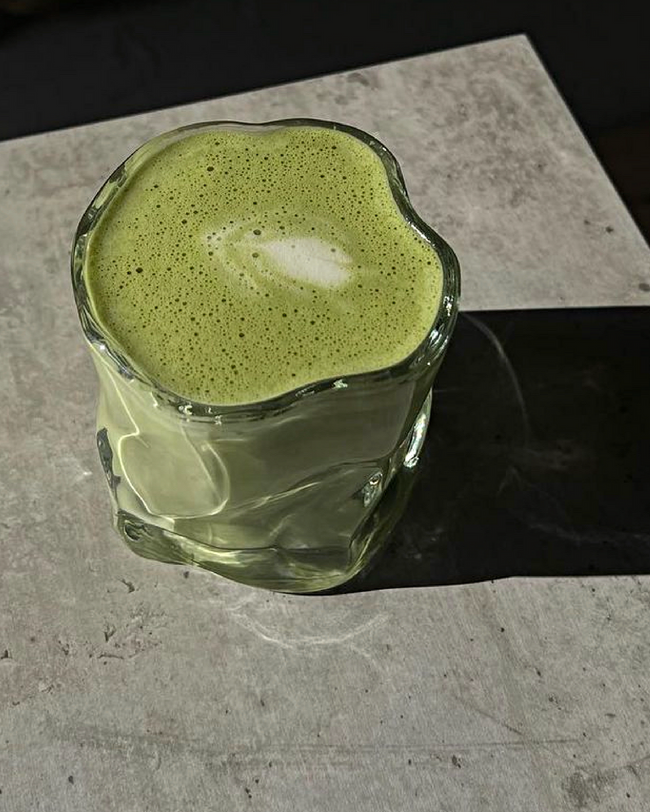 Išskirtinių formų stiklinė su paserviruota matcha latte arbata.